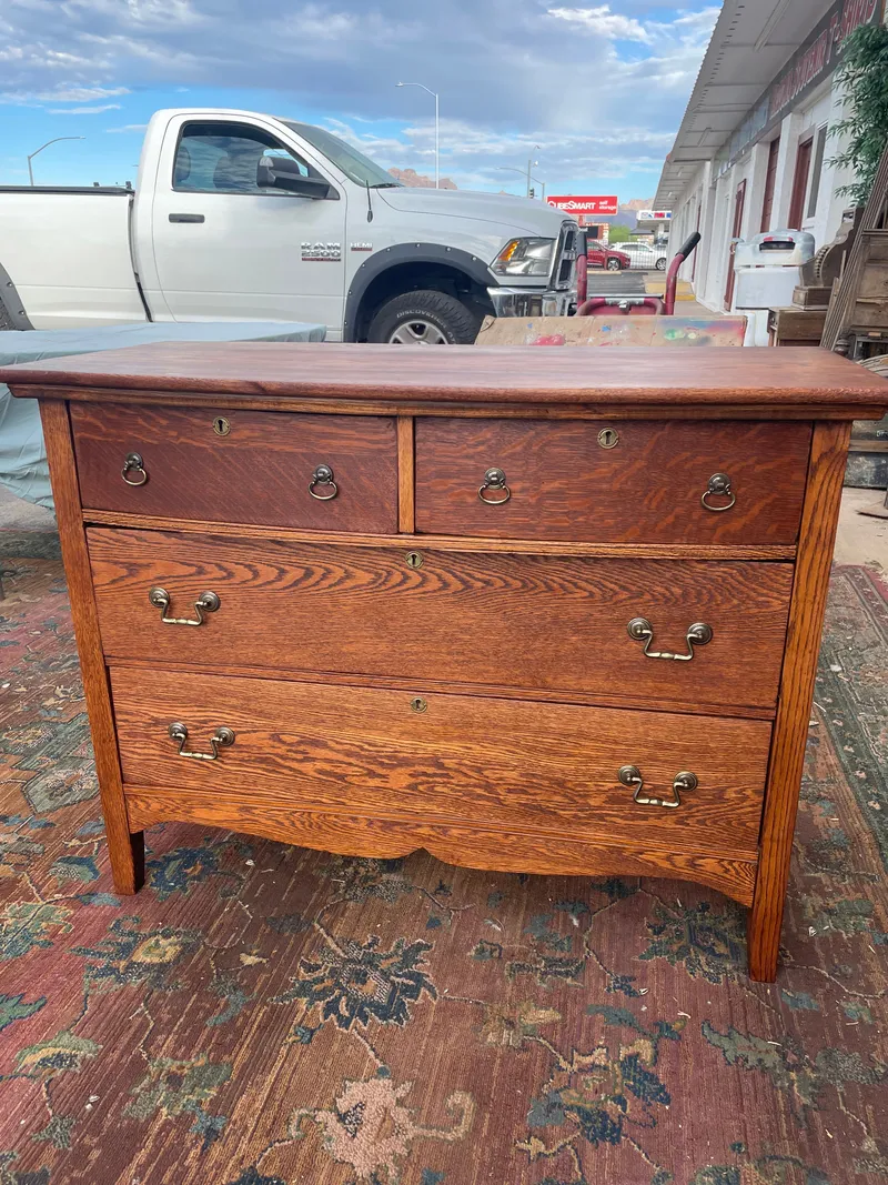 A refinished oak dresser with brass pulls on a rug outside Sample Studios