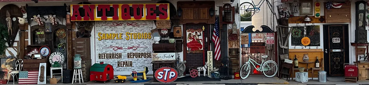 The Sample Studios storefront on Apache Trail: the Antiques sign and the Refurbish, Repurpose, Repair wall, with antiques along the walk