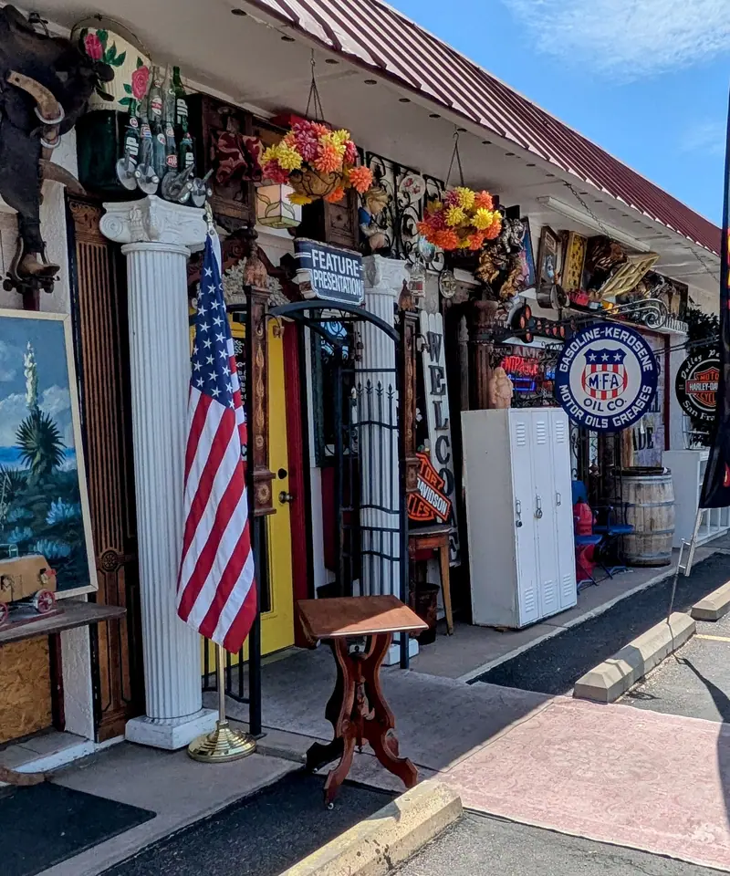 Covered walkway outside Sample Studios on W Apache Trail in Apache Junction, with an American flag by the door