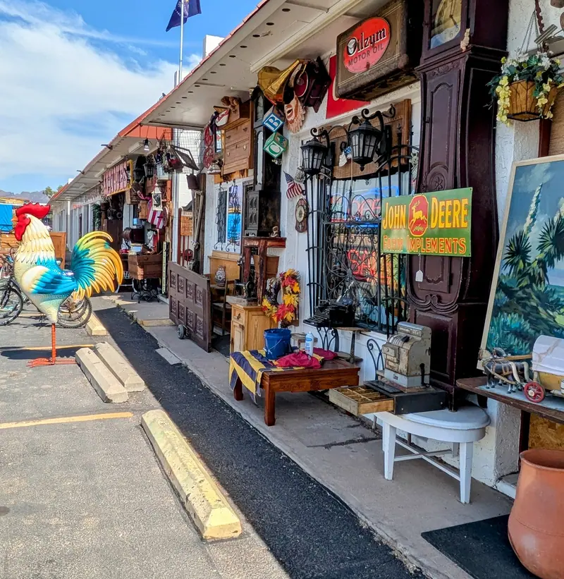 Parking spaces in front of Sample Studios, with antiques set out along the shaded walkway