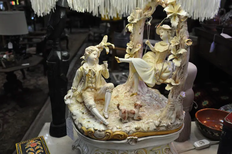 A porcelain figurine lamp with a fringed shade