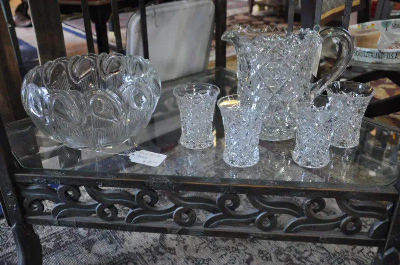 Pressed glass punch bowl, pitchers and tumblers on a wrought-iron table